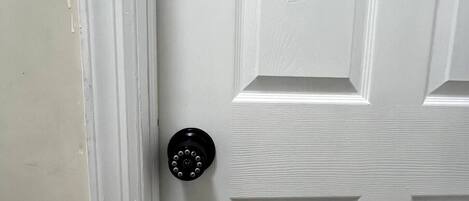 A white door with a textured panel and a black doorbell.