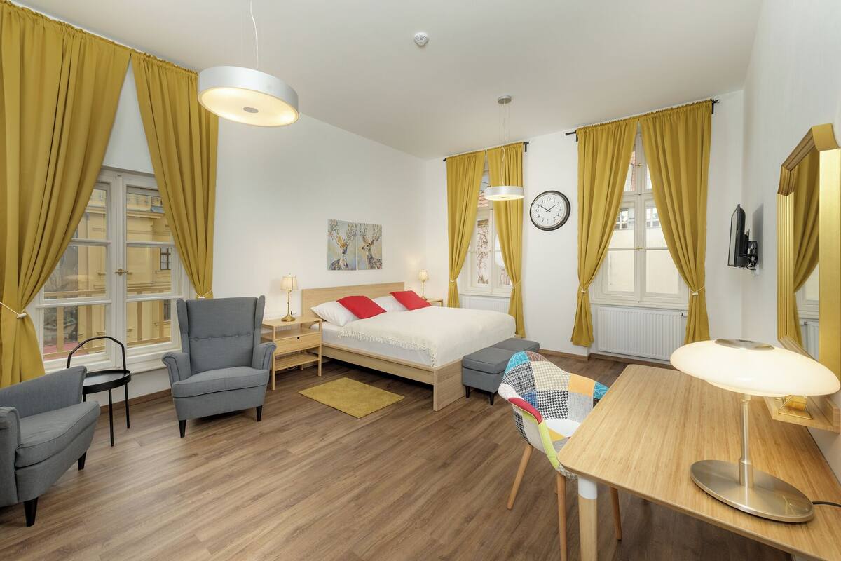 Una habitación de hotel moderna con una cama, dos sillones, un escritorio y una mesa de comedor.