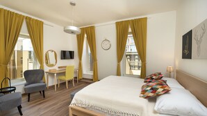 A hotel room with a bed, a desk, a chair, a TV, and a window with curtains. - Unesco Prague Apartments (Prague)