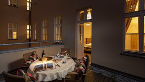 A dining area with a table set for two, featuring a candle, wine bottle, and plates. - Unesco Prague Apartments (Prague)