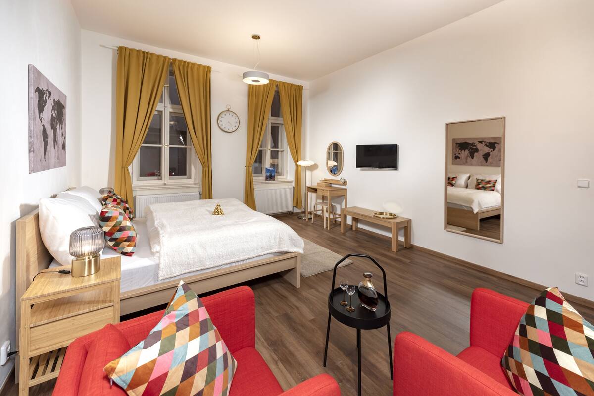 Una habitación de hotel moderna con una cama, un escritorio, una silla y un sofá rojo.