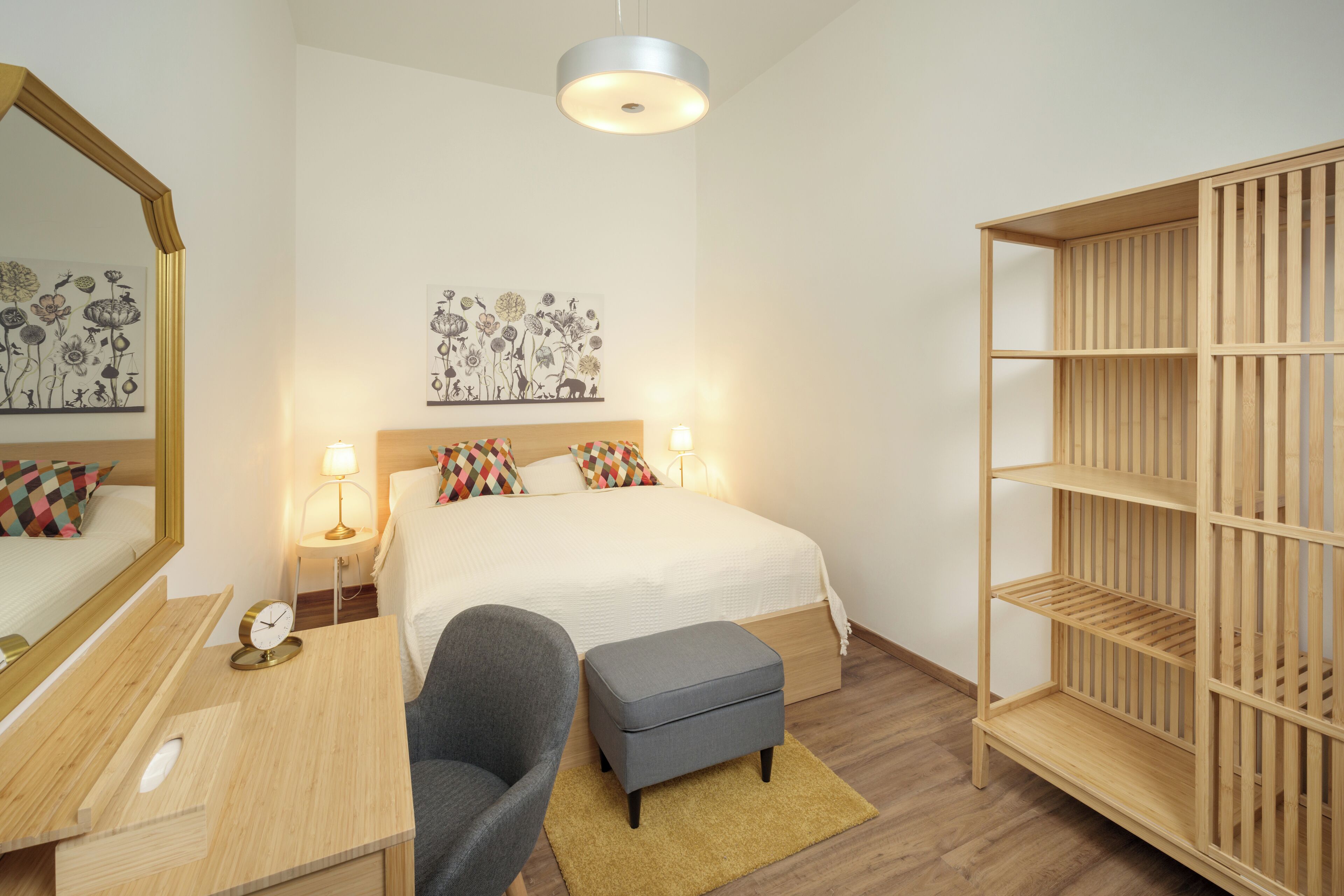 Un dormitorio con cama, mesitas de noche, escritorio, silla, armario y obras de arte en las paredes.