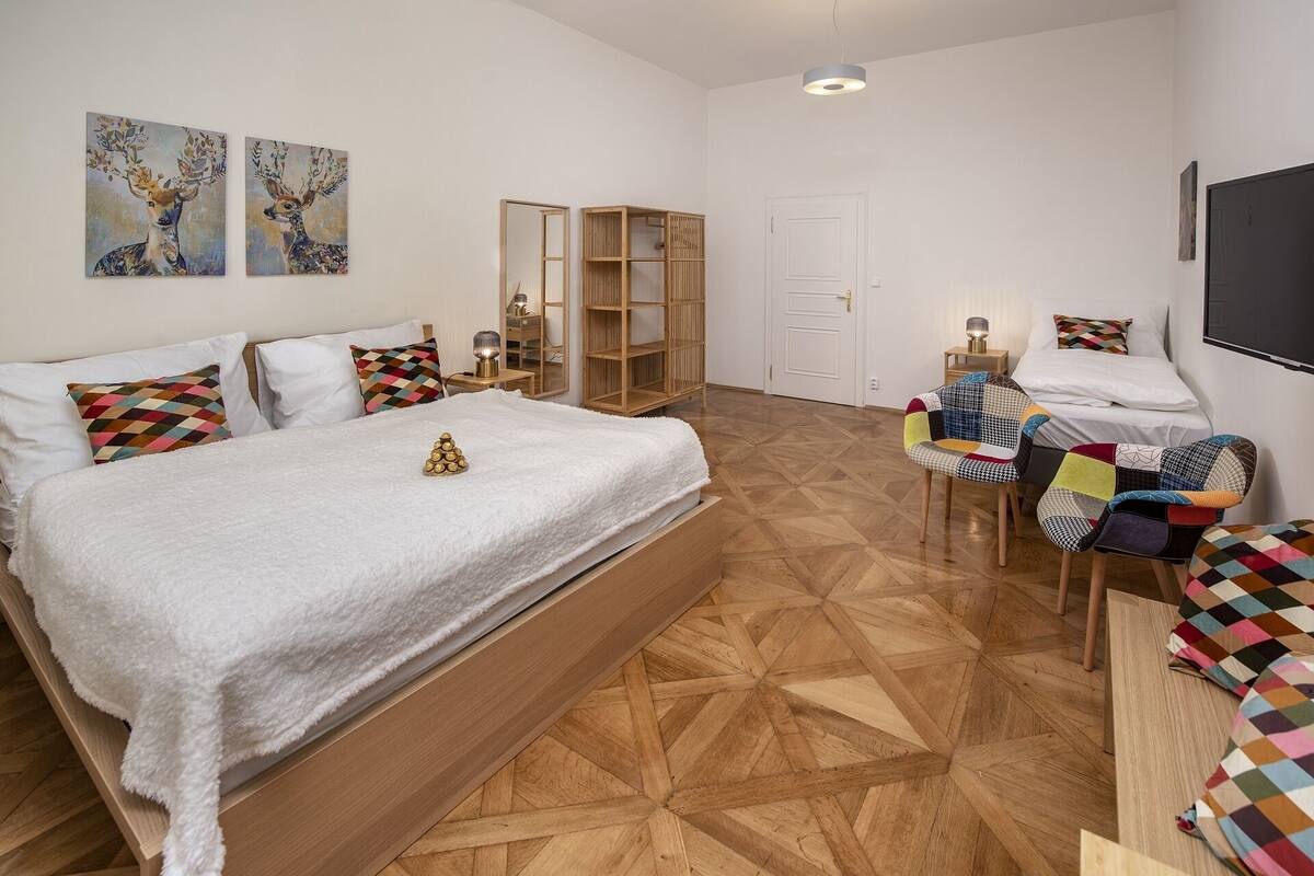 Un dormitorio con una cama grande, un armario de madera, un escritorio con una silla y dos cuadros en la pared.