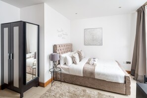 Relax in a serene bedroom with a large bed, bedside table, and mirror.