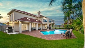 A two-story house with a swimming pool, a barbecue area, and a covered patio.