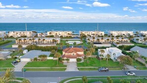 Zona residencial costanera amb diversos edificis blancs, una casa central amb teulada vermella i vista a l'oceà.