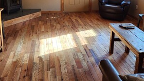 A room with wooden flooring, a black leather chair, a wooden table, and a fireplace. - Escape to Nature: Charming 3-Bedroom Cabin near Trinity Lake (Trinity Center)