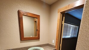 A bathroom with wooden cabinets, a granite countertop, a mirror, and a window with blinds. - Escape to Nature: Charming 3-Bedroom Cabin near Trinity Lake (Trinity Center)