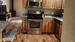 A kitchen with wooden cabinets, a stainless steel stove, and a microwave. - Escape to Nature: Charming 3-Bedroom Cabin near Trinity Lake (Trinity Center)