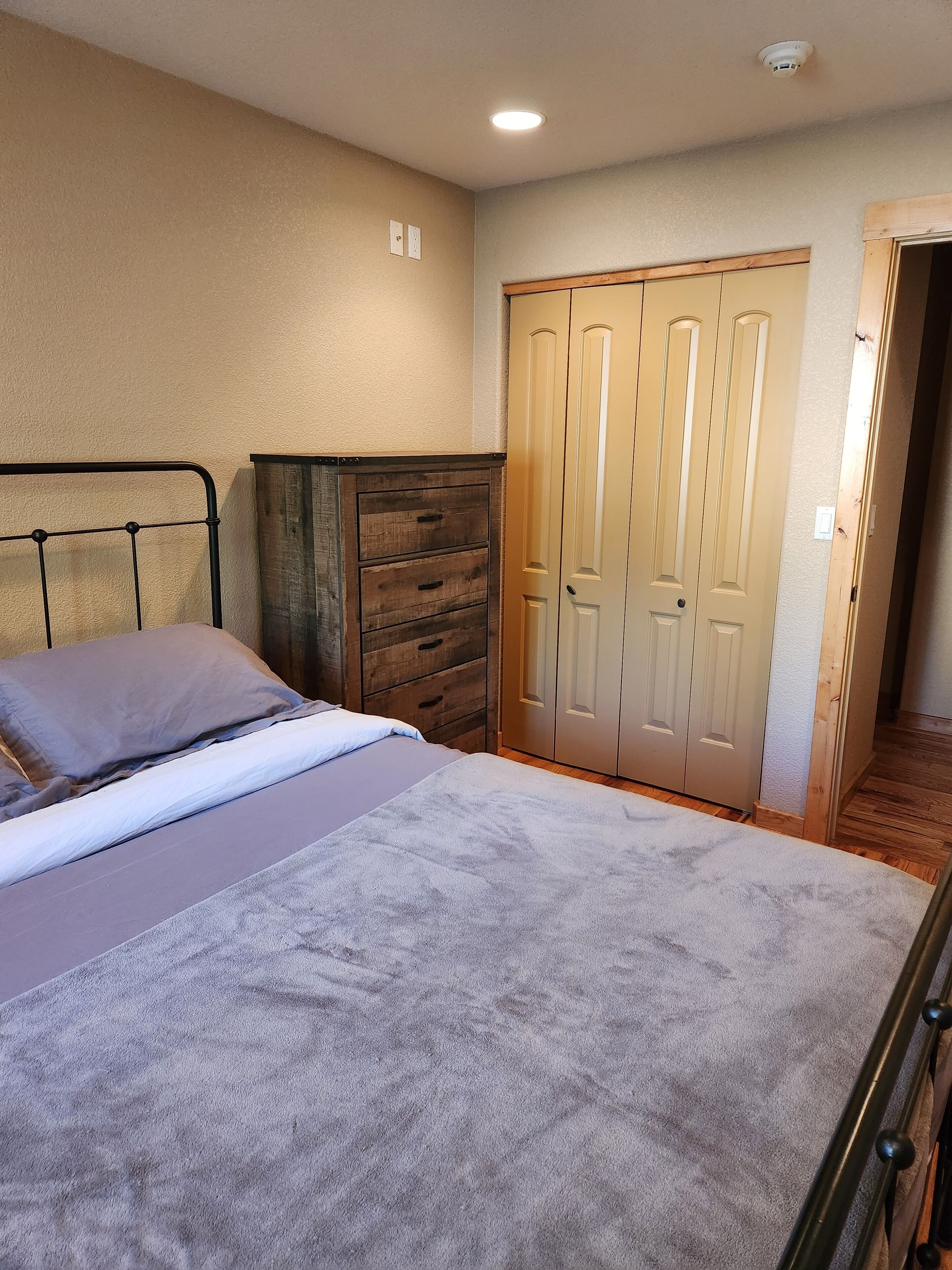 A bedroom with a bed, a dresser, and a wardrobe.