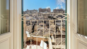 Vista a través de una ventana con reja de metal, que da a un pueblo histórico con edificios antiguos y cielo despejado.
