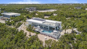 Una casa moderna de dos pisos con piscina, rodeada de vegetación tropical exuberante.