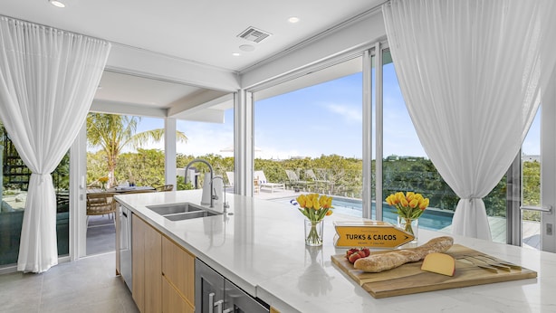 Una cocina moderna con una isla grande, vistas al exterior y un cartel que indica los servicios disponibles.