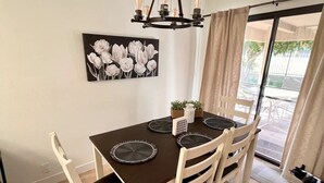 Ein Essbereich mit einem Tisch für vier Personen, einer Chandelierleuchtre und einem Blumenbild an der Wand.