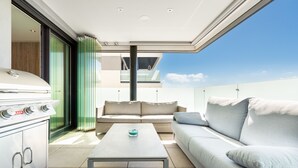 A modern outdoor living area with a sofa, a coffee table, and a grill.