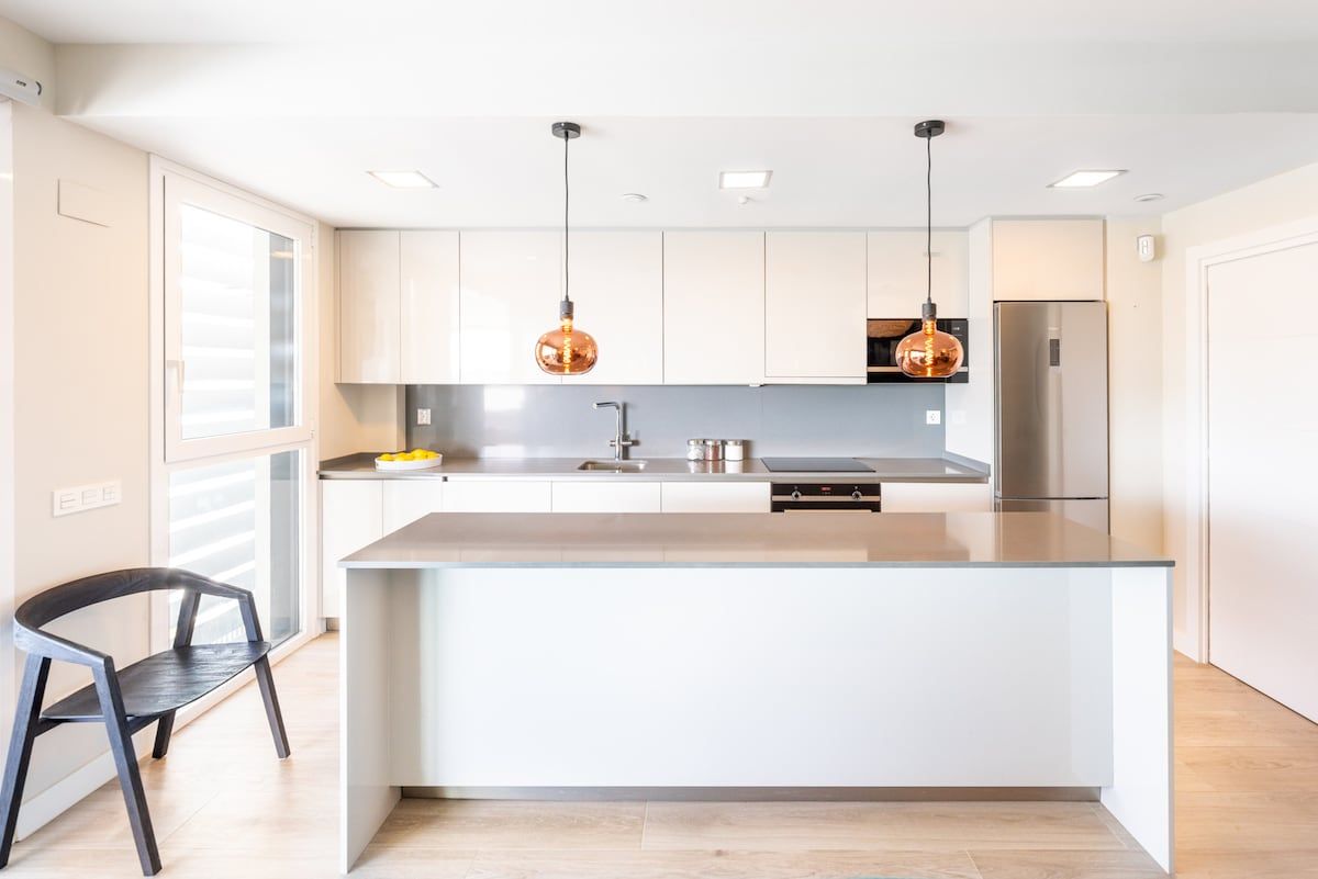 A modern kitchen with a central island, stainless steel appliances, and pendant lighting.