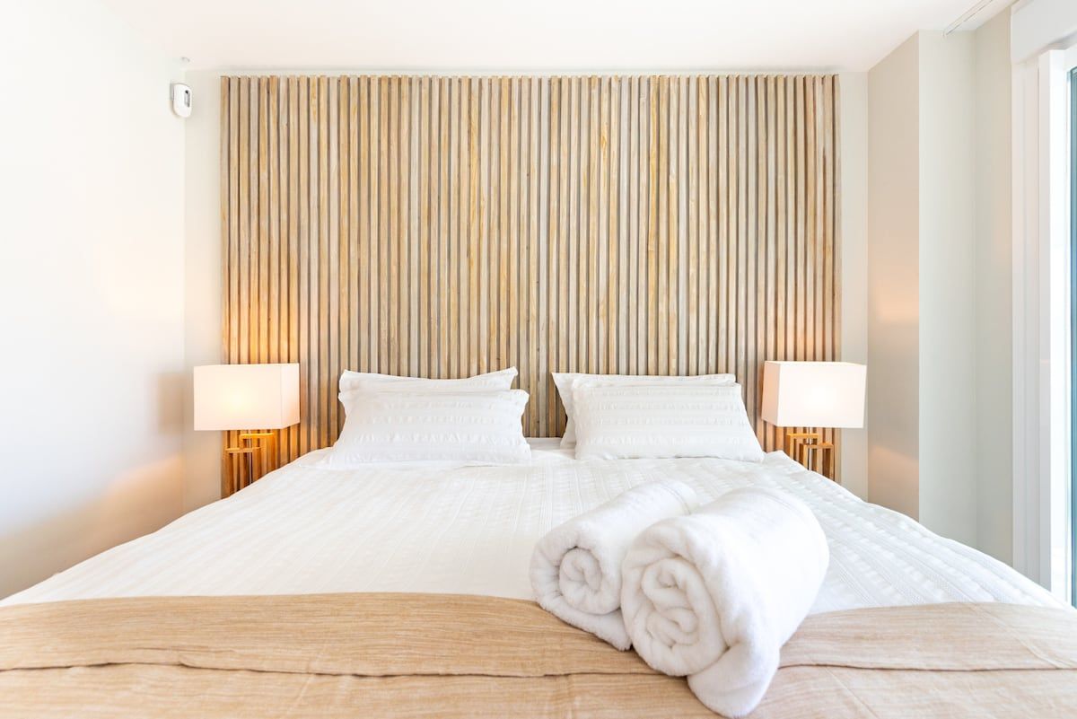 Habitación de hotel con una cama grande, dos lámparas de noche y un cabecero de madera.