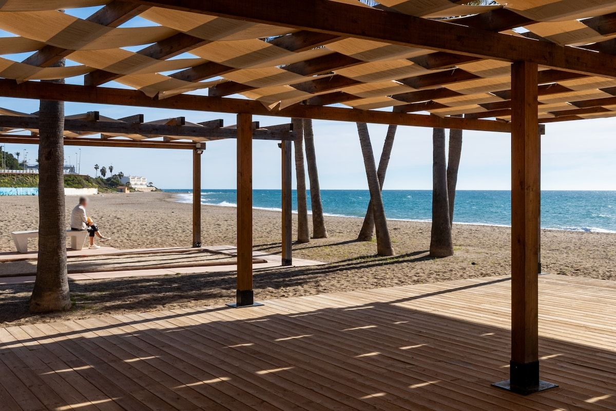 Una terraza de madera con vista a la playa y al océano.