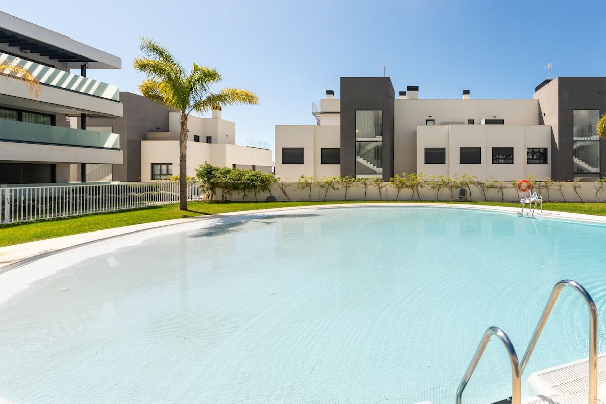 Un edificio moderno con piscina, una palmera y cielo despejado.