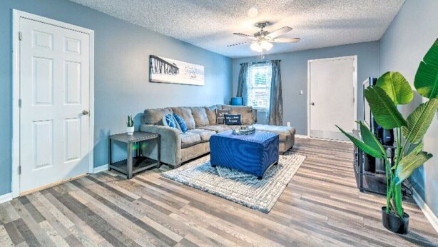 A living room with a sofa, coffee table, and a ceiling fan. - Condo Comforts of HOMME (Kannapolis)