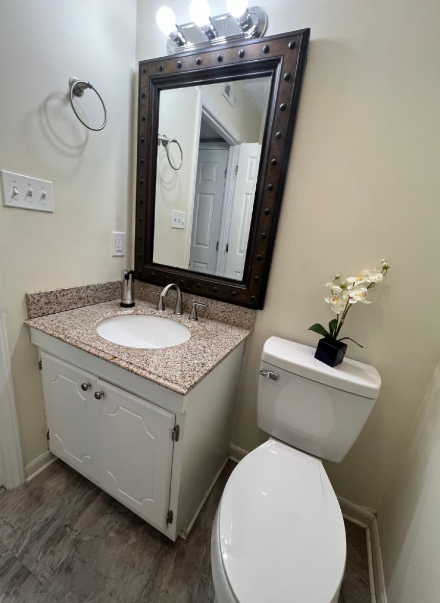 Une salle de bain avec un lavabo, un meuble-lavabo et des toilettes, le tout de couleur blanche.