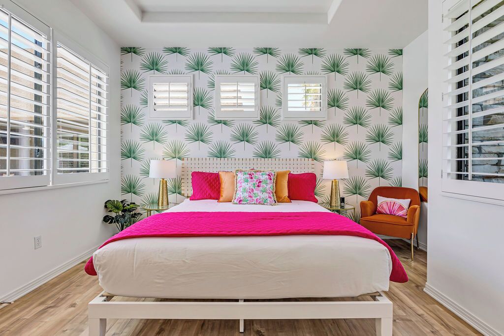 A bedroom with a bed, two bedside tables, a chair, and a window with blinds.