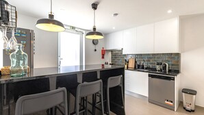 Una cucina moderna con un'area bar in bianco e nero, elettrodomestici in acciaio inossidabile e una parete backsplash rivestita di piastrelle.
