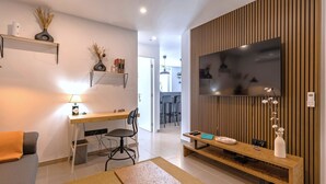 A modern living room with a TV, wooden panel wall, and a desk with a chair.