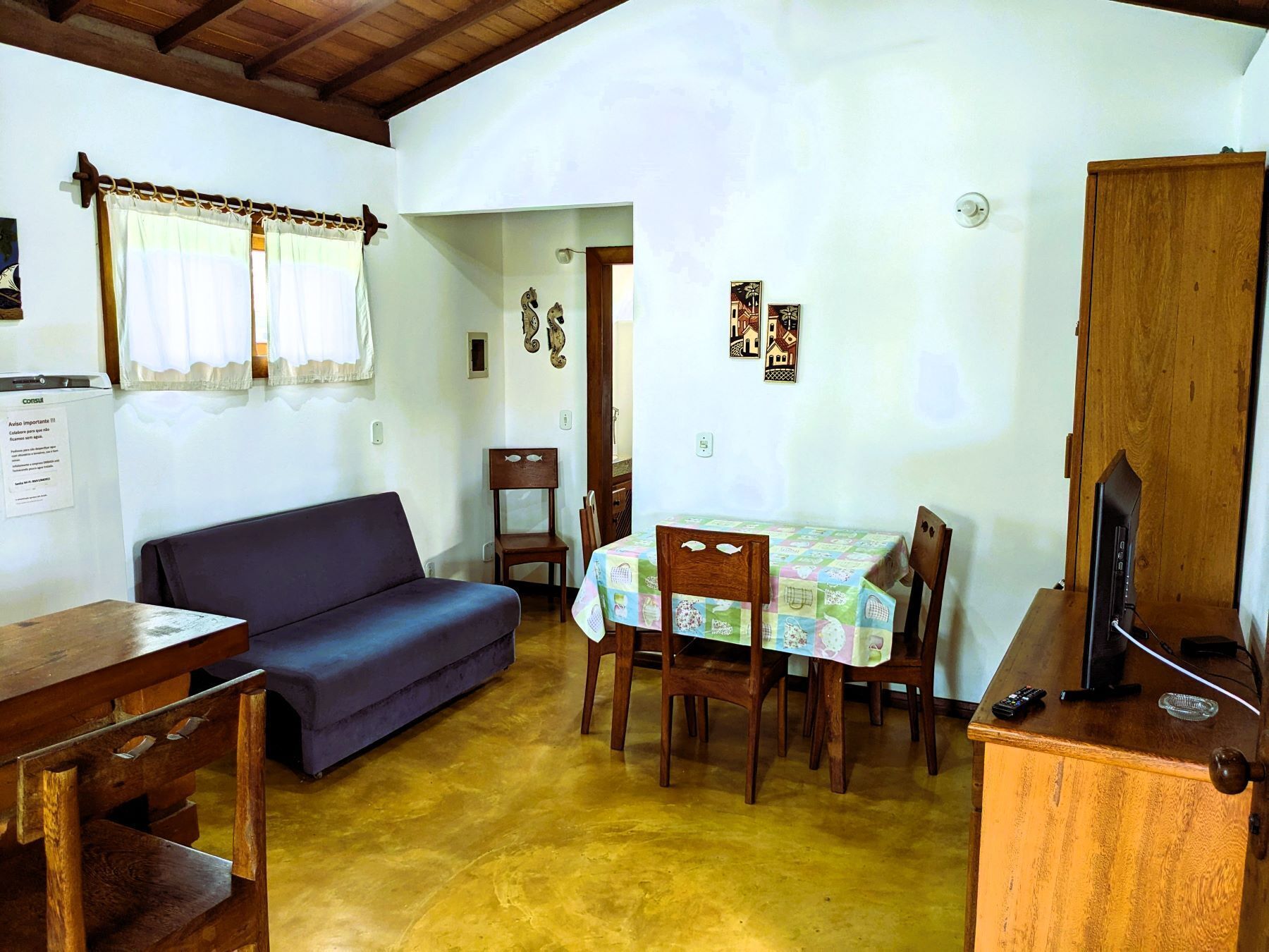 Um quarto aconchegante com sofá, mesa de jantar, cadeiras e televisão.