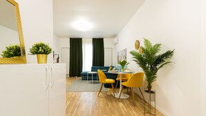 Una sala moderna con un sofá, una mesa de comedor, sillas y un espejo grande.
