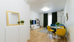 Una sala de estar moderna con un sofá blanco, sillas amarillas, una mesa de comedor y un espejo grande.