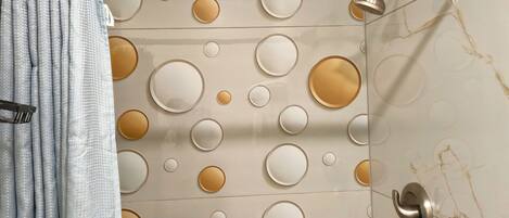 Un baño con cortina de ducha, toallero y pared con diseños circulares.