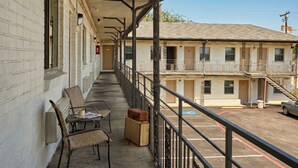 A motel with a covered balcony, outdoor seating, and a parking area. - Exclusivo Inn by OYO Grand Prairie, TX (Grand Prairie)