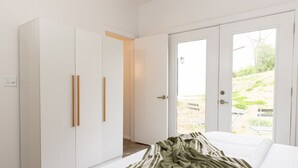 Ein Schlafzimmer mit einem Bett, einem Kleiderschrank und einer Schiebetür zu einem Außenbereich.