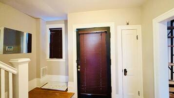 A hallway with a wooden floor, a dark brown door, and a white door.