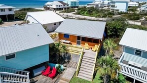Un quartier résidentiel situé sur la côte, avec des maisons, une terrasse en bois et une vue sur l’océan.