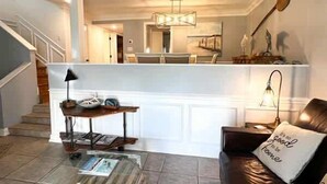 A living room with a leather sofa, a coffee table, a lamp, and a wall-mounted shelf with decorative items.