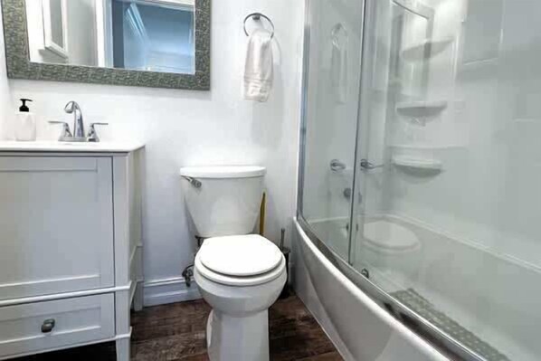 A bathroom with a toilet, sink, and shower area.