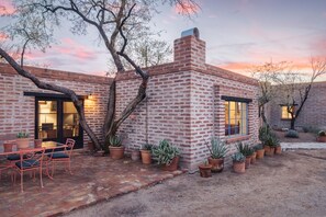A brick building with a patio, outdoor seating, and potted plants.