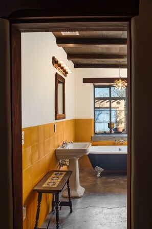 A bathroom with a bathtub, sink, and a wooden bench.