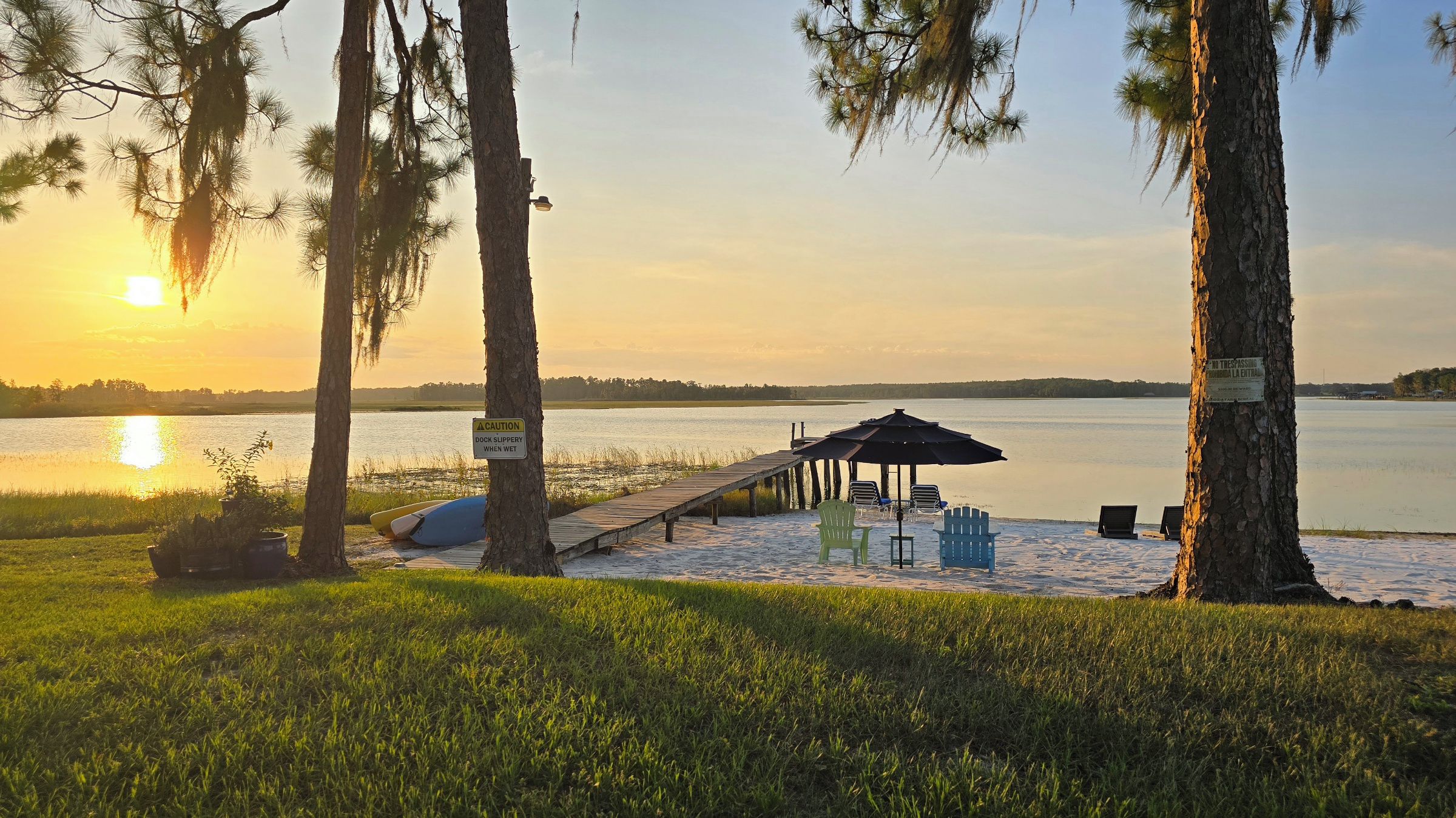 A beach with a wooden pier, lounge chairs, and a gazebo.