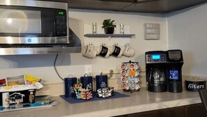 Eine Küche mit Mikrowelle, Kaffeemaschine und Tassen auf der Arbeitsfläche.