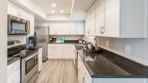 A modern kitchen with white cabinets, stainless steel appliances, and a granite countertop. - Private Pool + NEW Luxury Hot Tub | 15 Min Beach (Bradenton)
