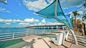 A waterfront promenade with a bridge in the background, a metal sculpture, and palm trees. - Private Pool + NEW Luxury Hot Tub | 15 Min Beach (Bradenton)