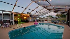 A covered outdoor swimming pool with a glass ceiling, lounge chairs, and a patio area with a table and chairs. - Private Pool + NEW Luxury Hot Tub | 15 Min Beach (Bradenton)
