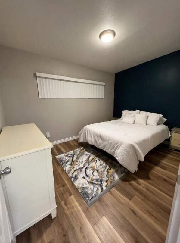 A bedroom with a bed, a nightstand, a dresser, and a window with blinds. - Modern, Comfortable 3bd w/ Backyard Space & Grill (Torrance)