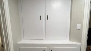 A white wardrobe with two doors and two drawers, located in a corner of a room with wooden flooring. - Modern, Comfortable 3bd w/ Backyard Space & Grill (Torrance)
