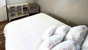 A bedroom with a bed, a window, a painting, and a cabinet. - Modern, Comfortable 3bd w/ Backyard Space & Grill (Torrance)