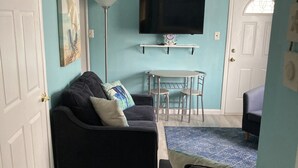 Una sala de estar con un sofá, una mesa de centro y un televisor montado en la pared.