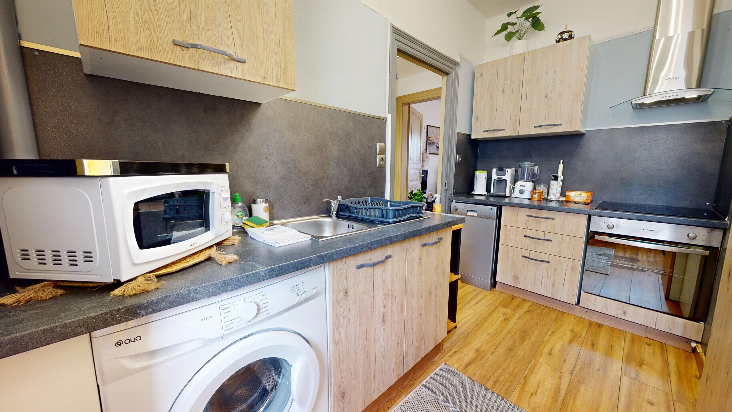 A compact kitchen with a washing machine, microwave, and modern appliances.